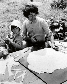 MIROSLAV ŠUTEJ izrađuje kolaž dok uz njega sjedi sin Šimun, 1971.
